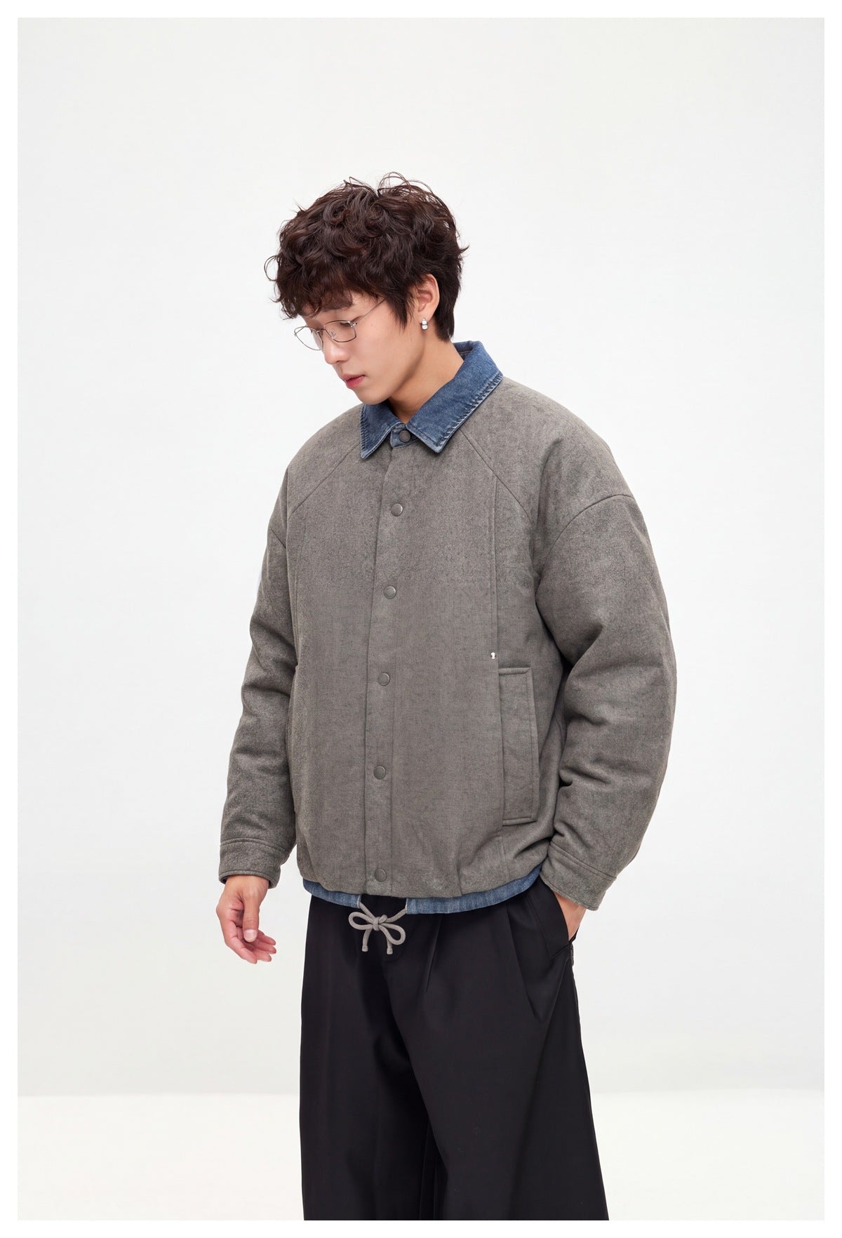 Side view of a model wearing a gray button-front jacket with a blue denim collar and front pocket.