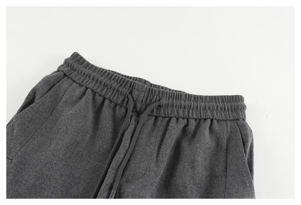 Close-up of charcoal gray pants showing the elastic waistband, drawstring, and pocket opening.