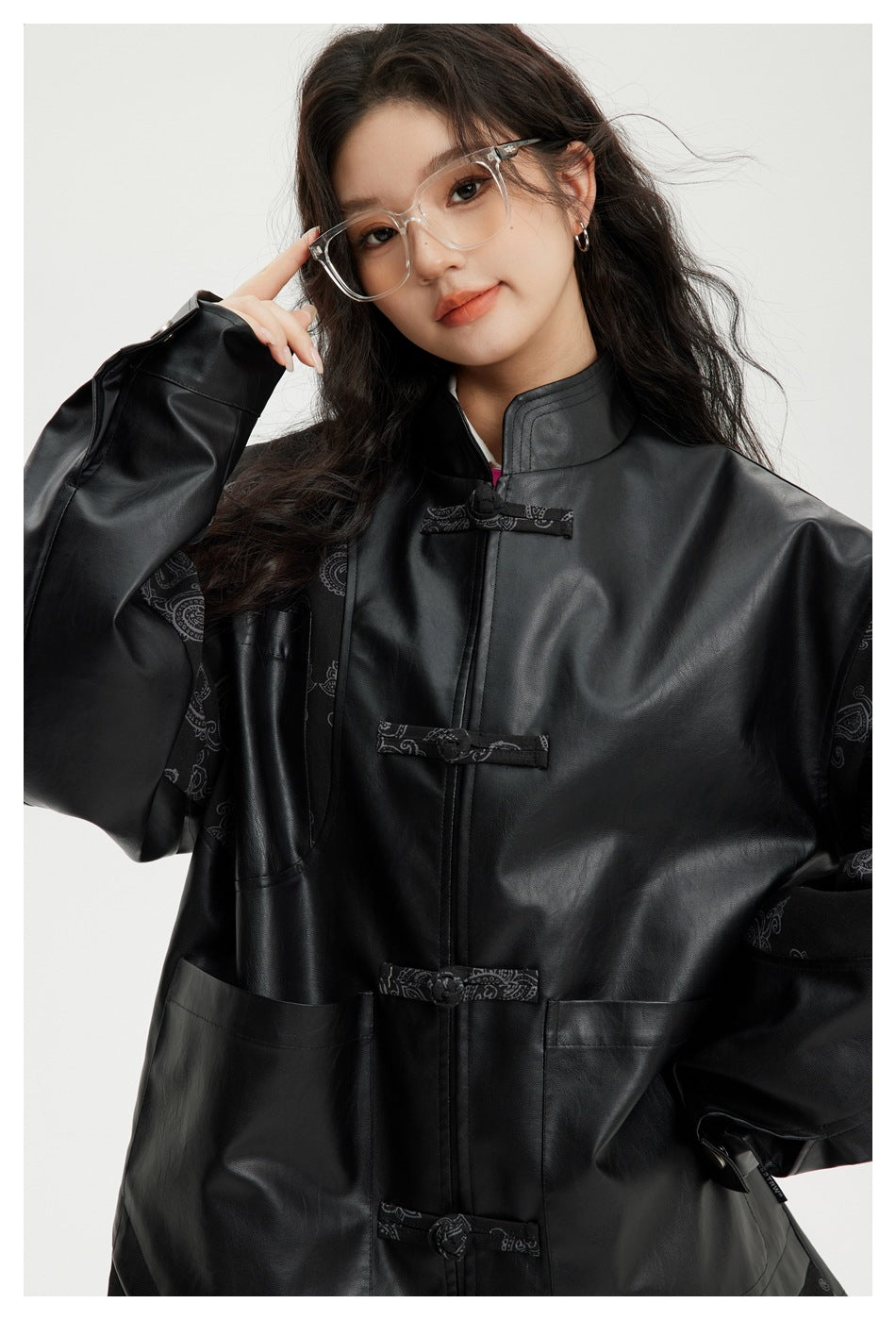 Close view of a model wearing a black jacket with paisley sleeve panels, a stand collar, and frog closures.