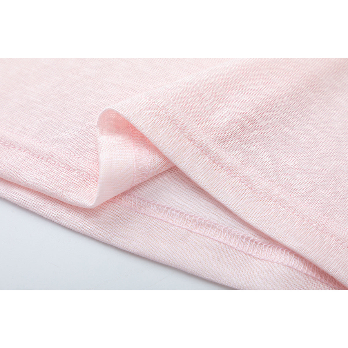 Close-up of pale pink shirt fabric and finished hem stitching.