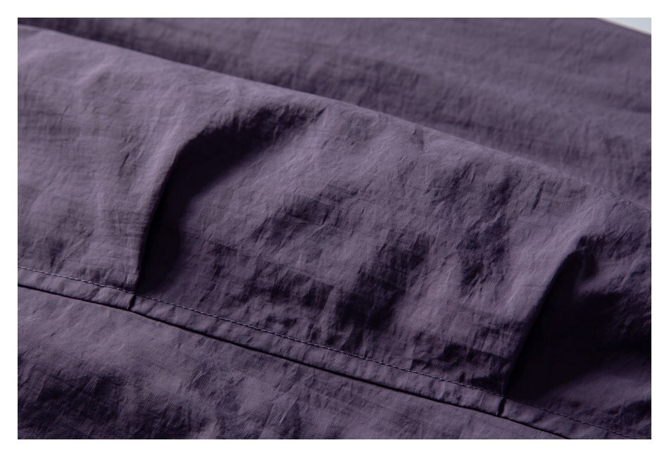 Close-up of purple garment fabric with a stitched seam and textured finish.
