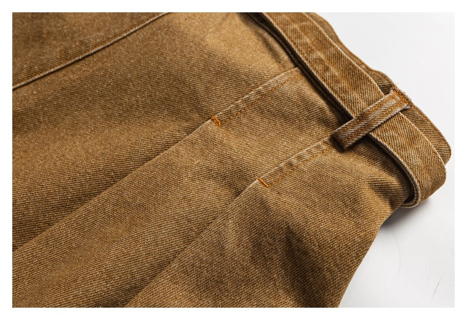 Close-up of brown pants showing a belt loop, waistband, and stitched panel seams.