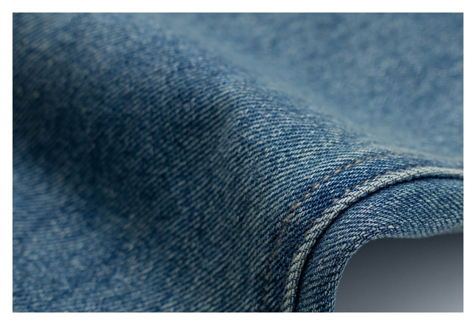 Macro view of blue denim fabric and a curved stitched seam.