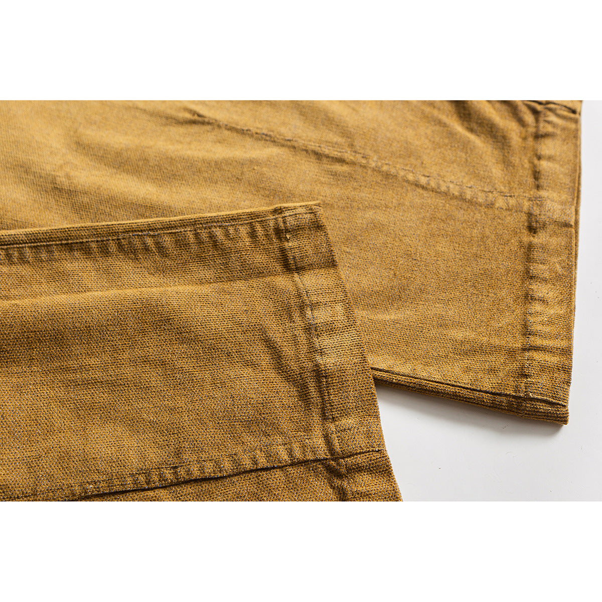 Close-up of ochre trouser legs showing the stitched hems and textured surface.