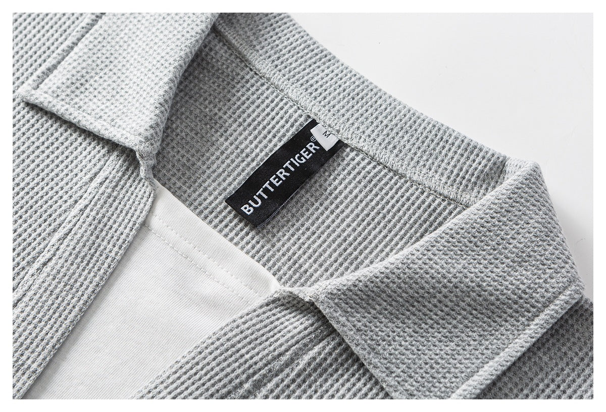 Close-up of a gray textured polo collar, white inner layer, and sewn black neck label.