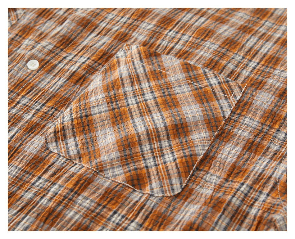 Close-up of a patch pocket on an orange, gray, and cream plaid shirt.