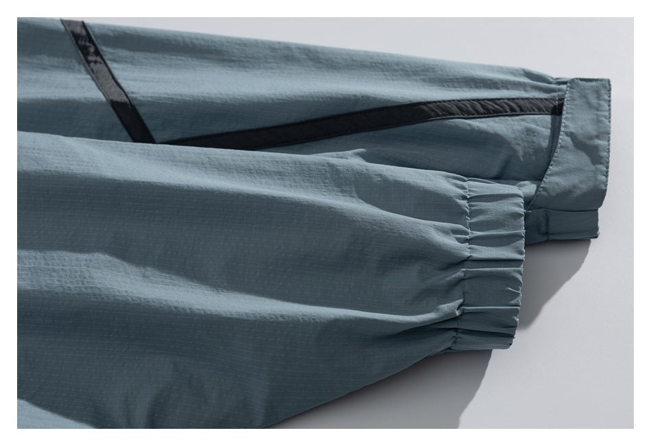 Close-up of a blue-gray sleeve ending in a gathered elastic cuff, with dark trim along the garment.