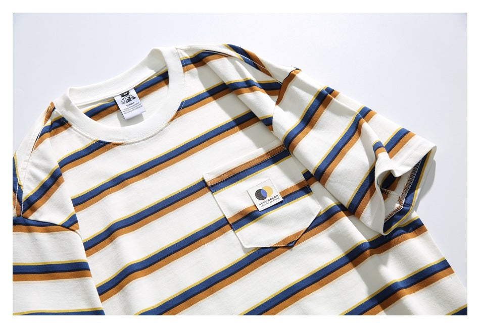Angled close view of a cream striped T-shirt front, showing its chest pocket and sewn logo patch.