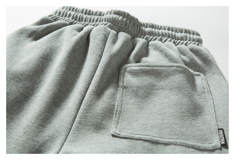 Close-up of light gray joggers showing an elastic waistband and a rectangular back pocket.