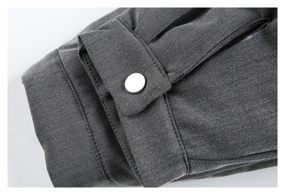 Close-up of a silver snap fastening on a charcoal gray fabric tab, with a narrow stitched opening nearby.