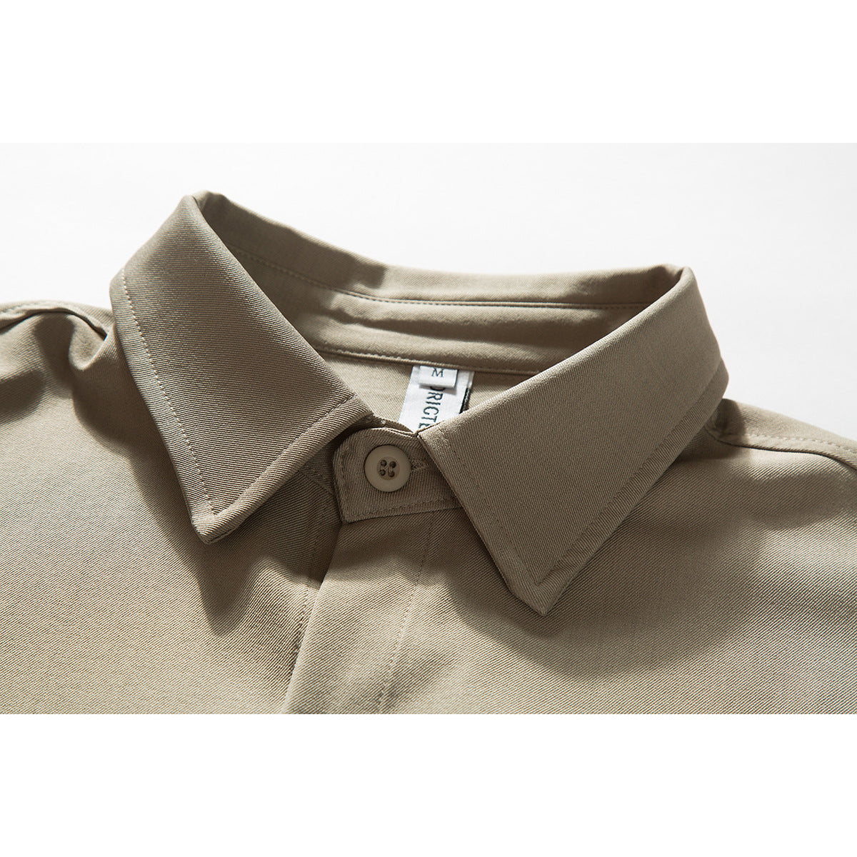 Close-up of a taupe button-up shirt collar, top button, and visible neck label.
