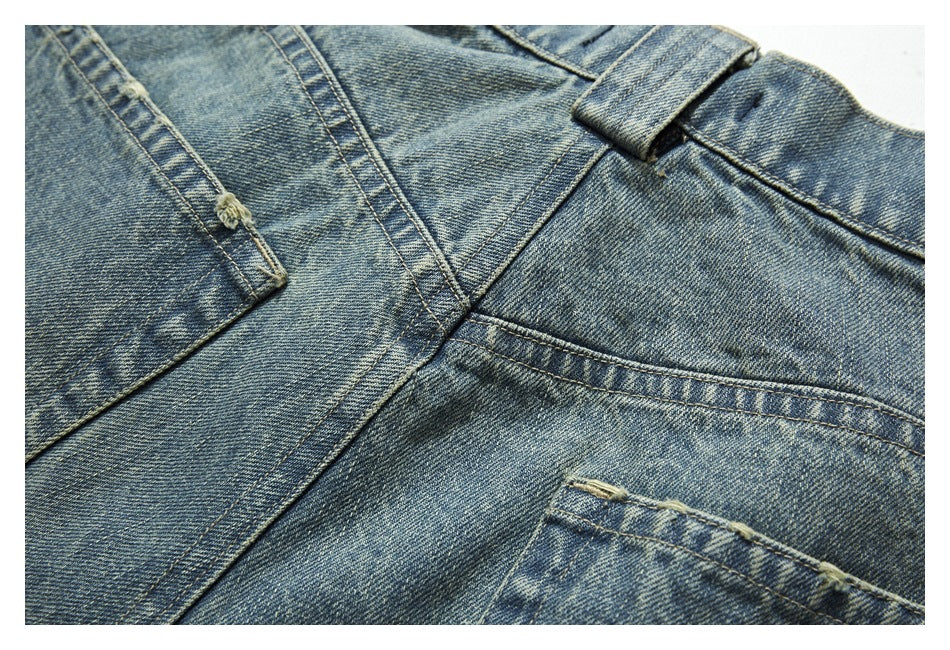 Close-up of faded blue denim jeans showing the waistband, belt loop, seams, and pocket stitching.