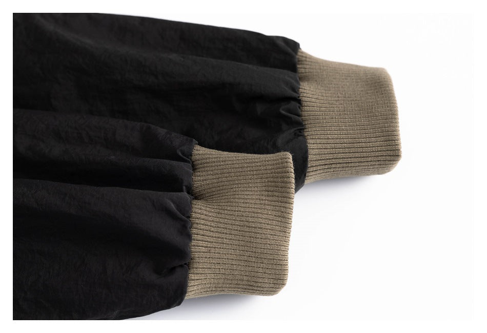 Close-up of black jacket sleeves with wide olive-brown ribbed cuffs.