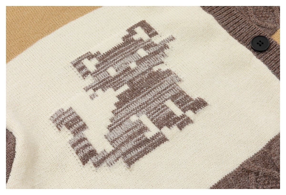 Close-up of a brown graphic knitted into an ivory panel, with the cardigan's brown trim and button visible.