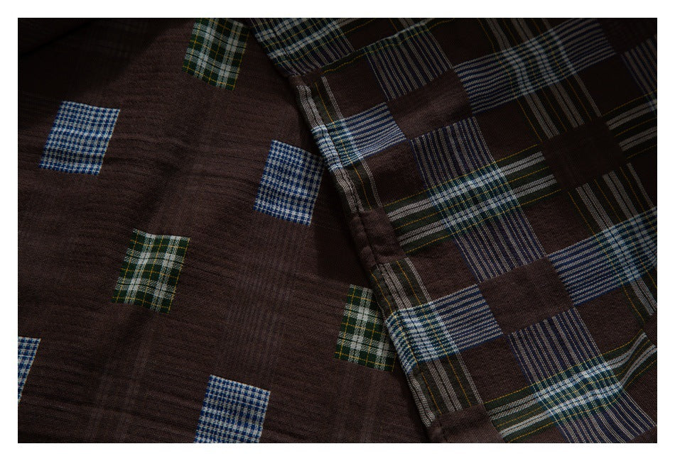 Close-up of dark brown fabric with scattered small plaid blocks beside a larger blue, green, and cream plaid pattern.