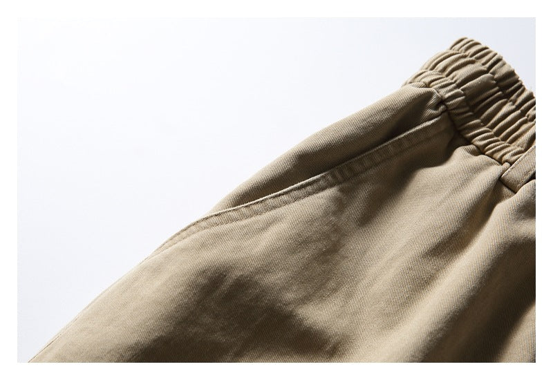 Close-up of khaki trouser fabric and stitching near the gathered elastic waistband.