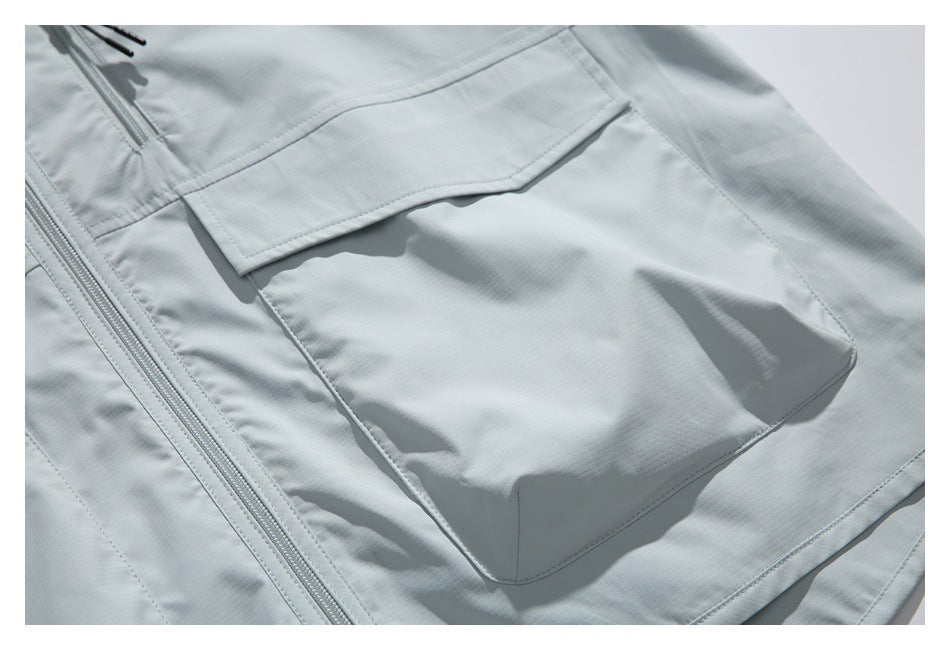 Close-up of a large flap pocket on the pale gray jacket's front.