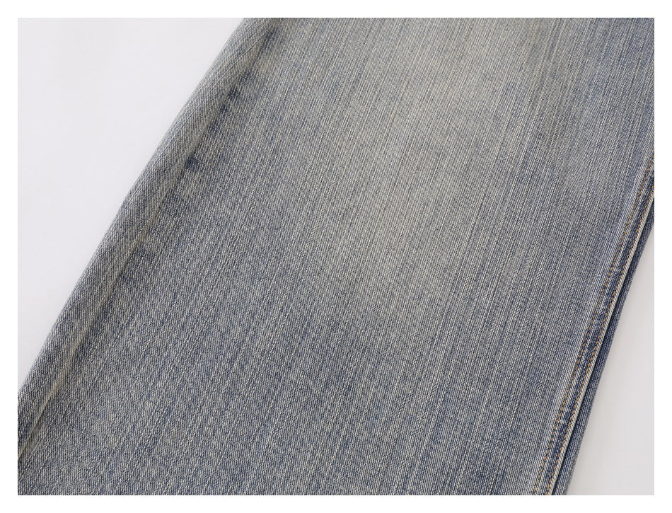 Close-up of a faded blue denim leg with subtle vertical wear and a stitched side seam.