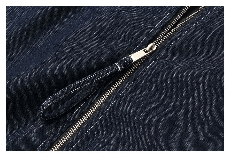 Close-up of a silver zipper and stitched placket on dark indigo denim.