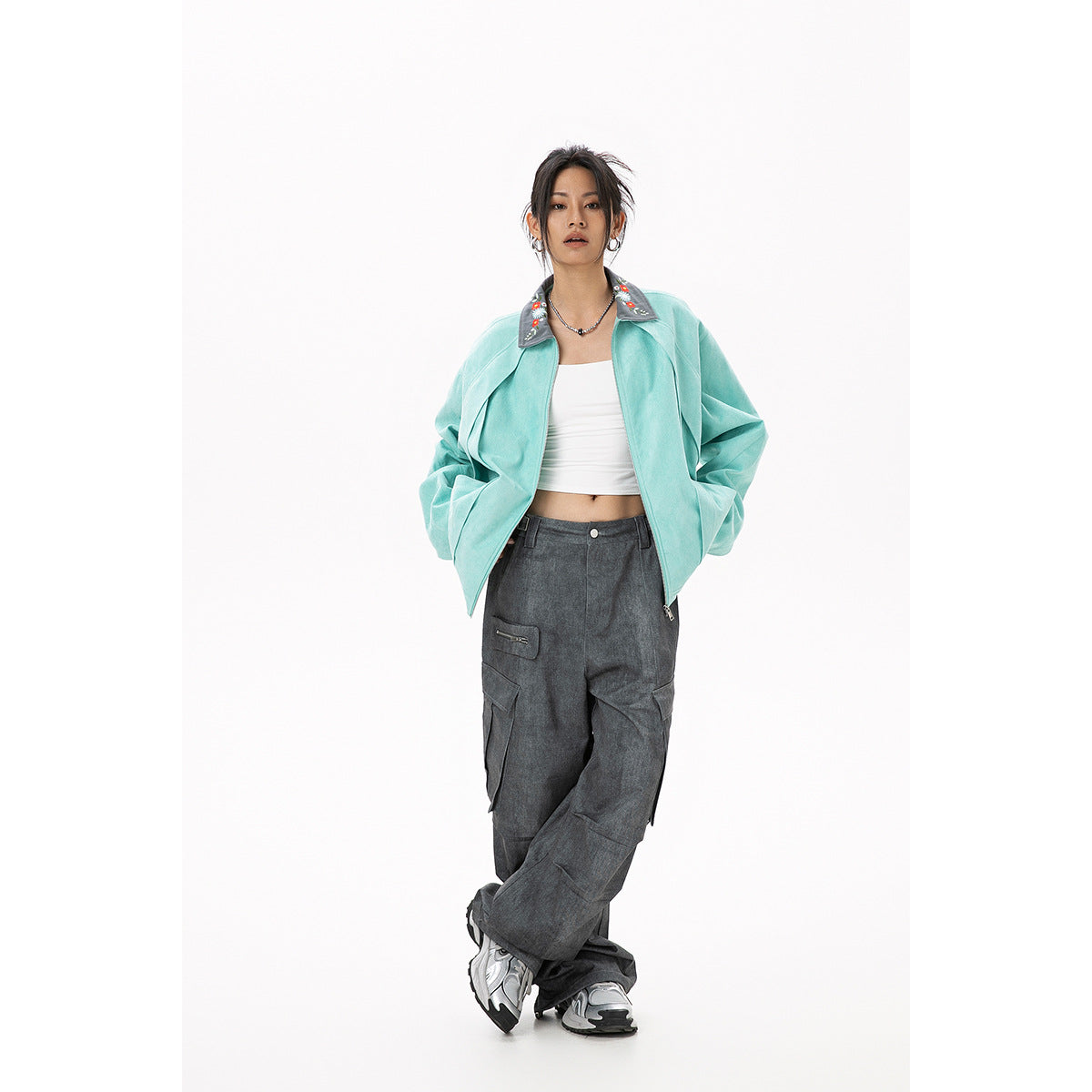 Front view of a model wearing an open mint jacket with a gray floral collar and charcoal cargo pants.