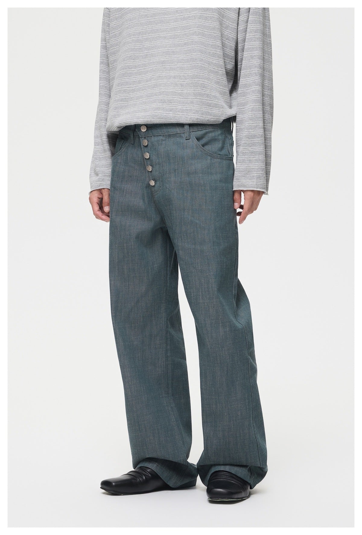 Model wearing blue-teal straight wide-leg jeans with asymmetric five-button front and gray striped long-sleeve top