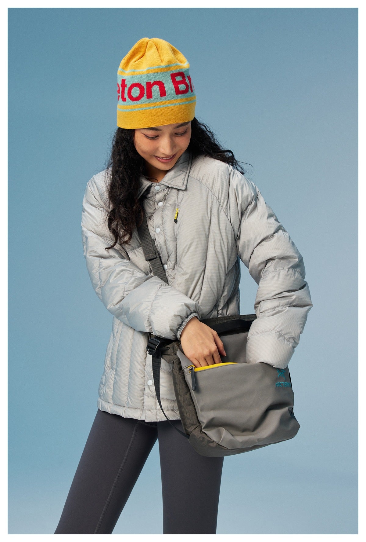 Woman in the gray quilted jacket with beanie and crossbody bag, close-up of collar, snaps and elastic cuff