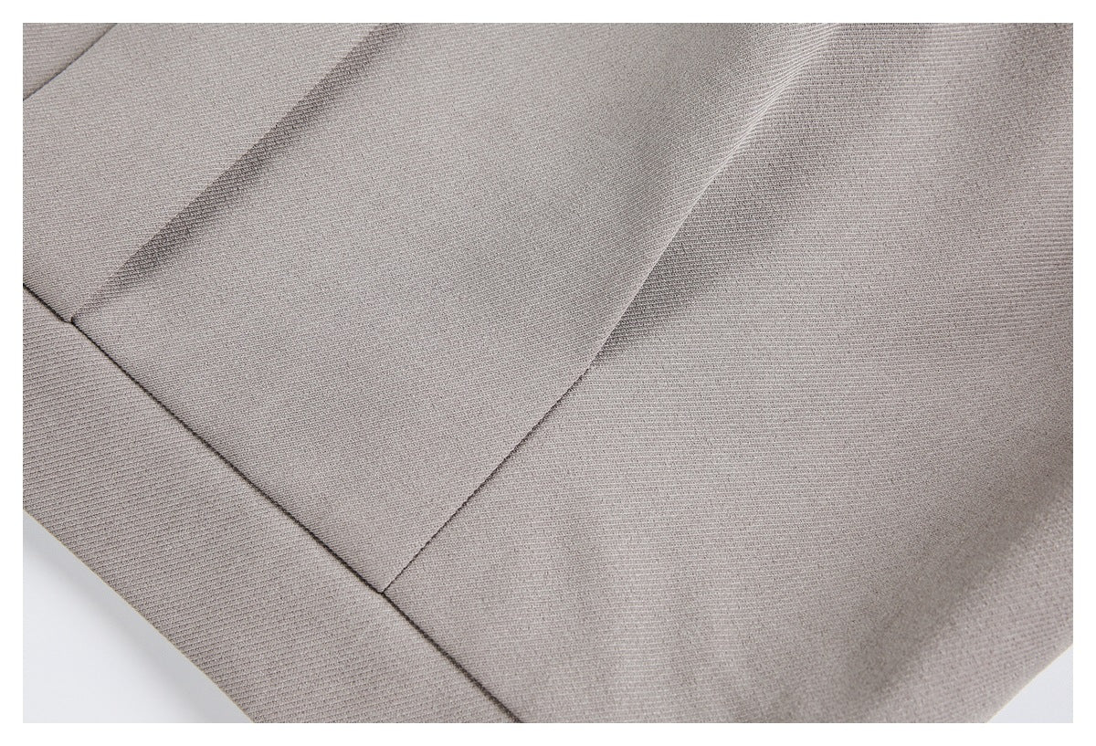 Close-up of taupe garment fabric showing intersecting seams and a wide stitched panel.