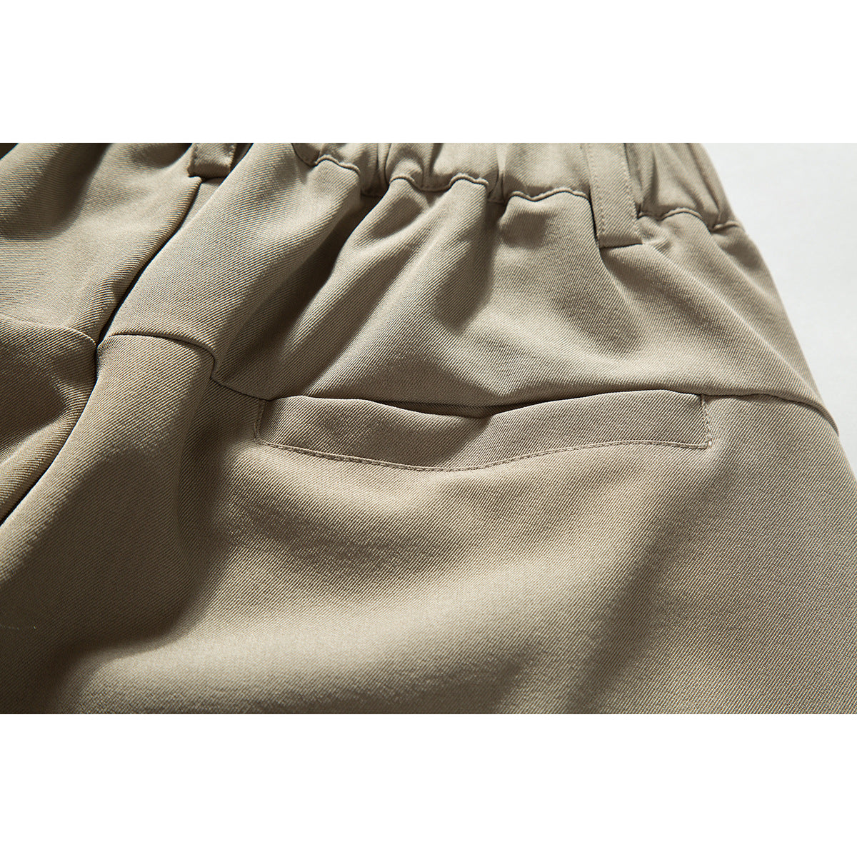 Close-up of a horizontal pocket on beige shorts below the gathered waistband.