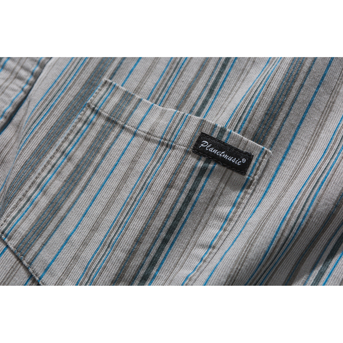 Close-up of a gray shirt pocket in blue and charcoal stripes, with a small black fabric label.