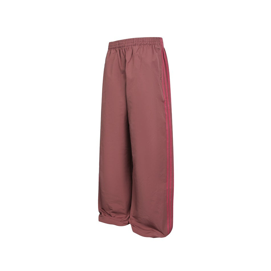 Angled view of dusty rose wide-leg pants with an elastic waist, side pockets, and darker stripes along the outer leg.