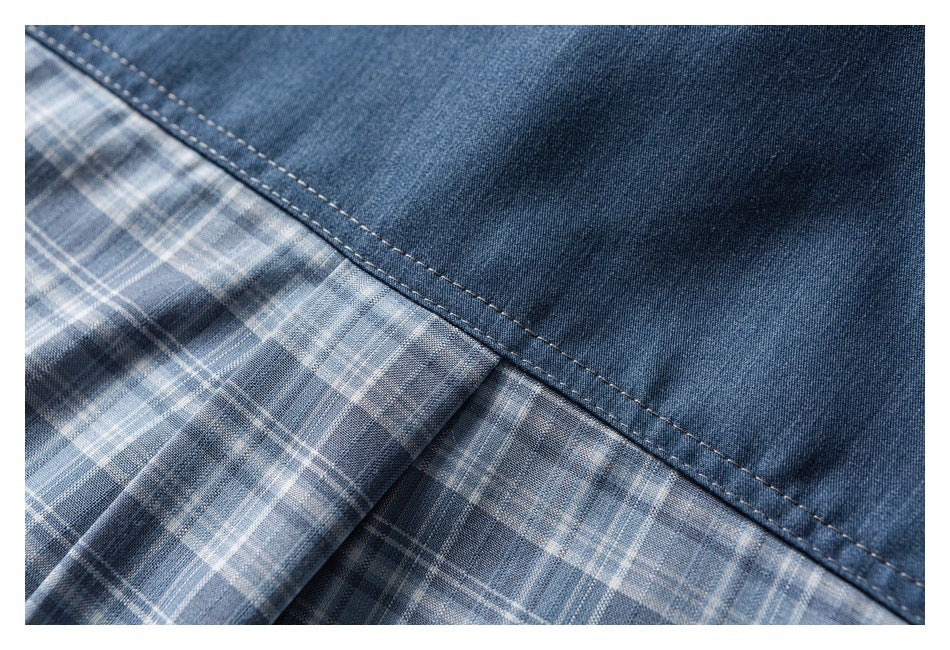 Close-up of a blue denim panel stitched over blue-gray plaid fabric.