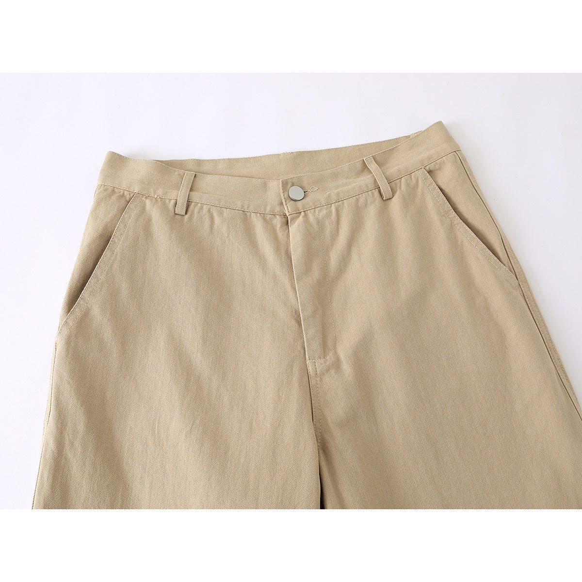 Close-up of tan wide-leg trousers showing the waistband, button, belt loops and angled front pockets.