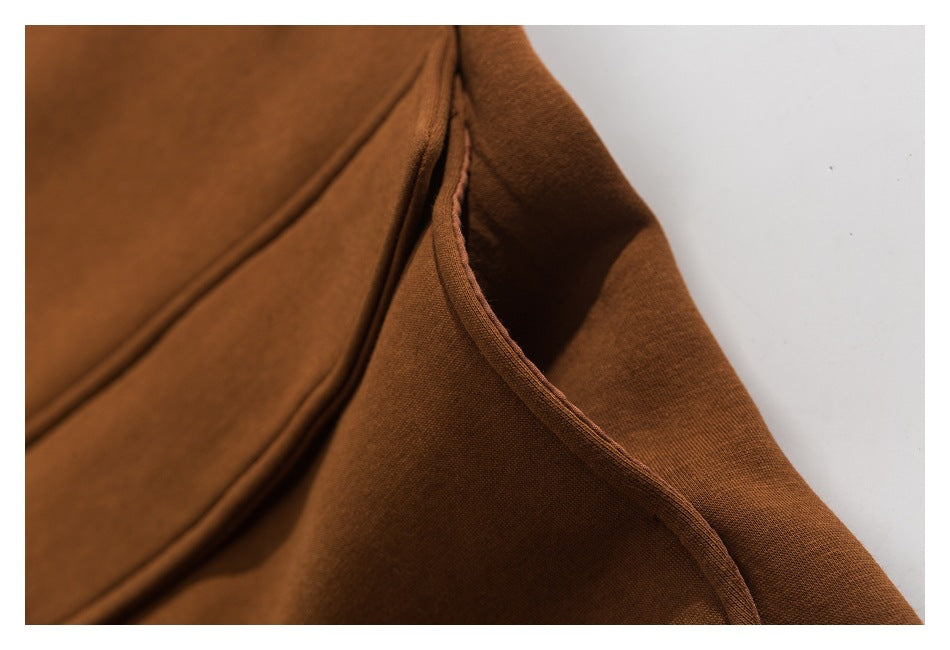 Close-up of the rust-brown coat's side pocket opening and stitched edge.