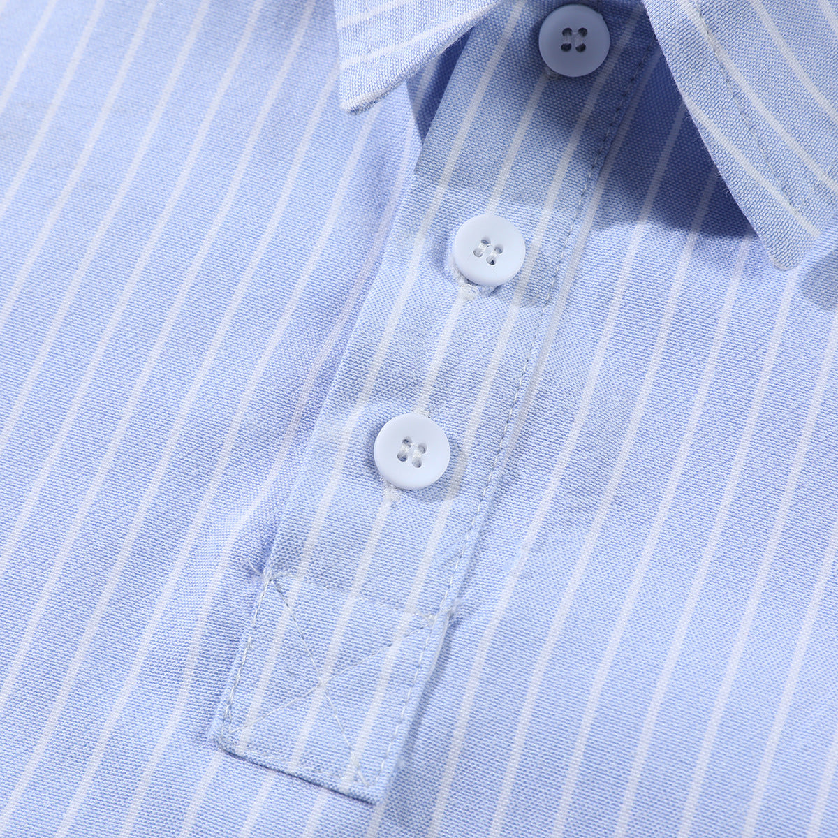 Close-up of a light blue striped shirt's collar and white button placket.