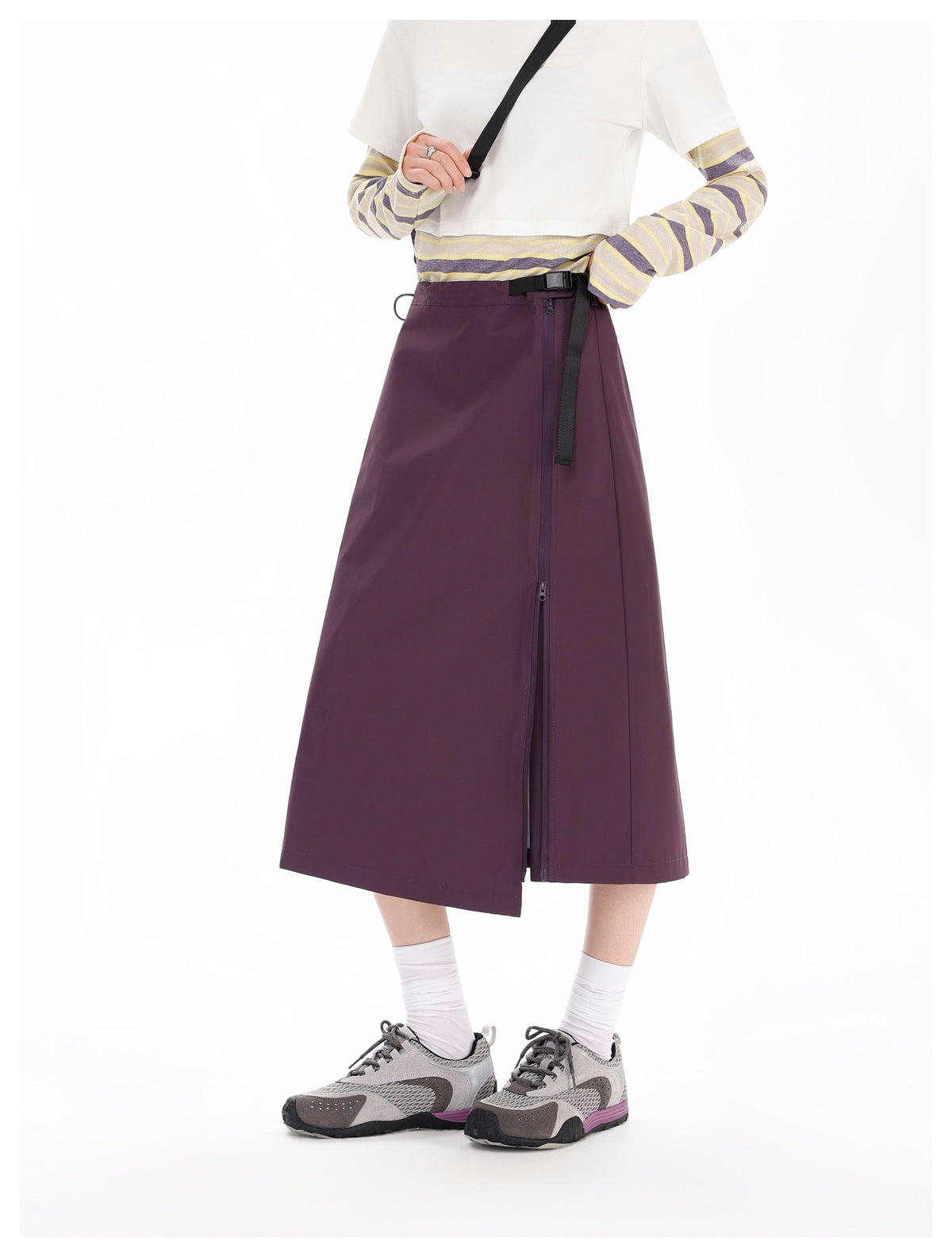 Model wearing a plum midi skirt with a black buckle belt and long side zipper.