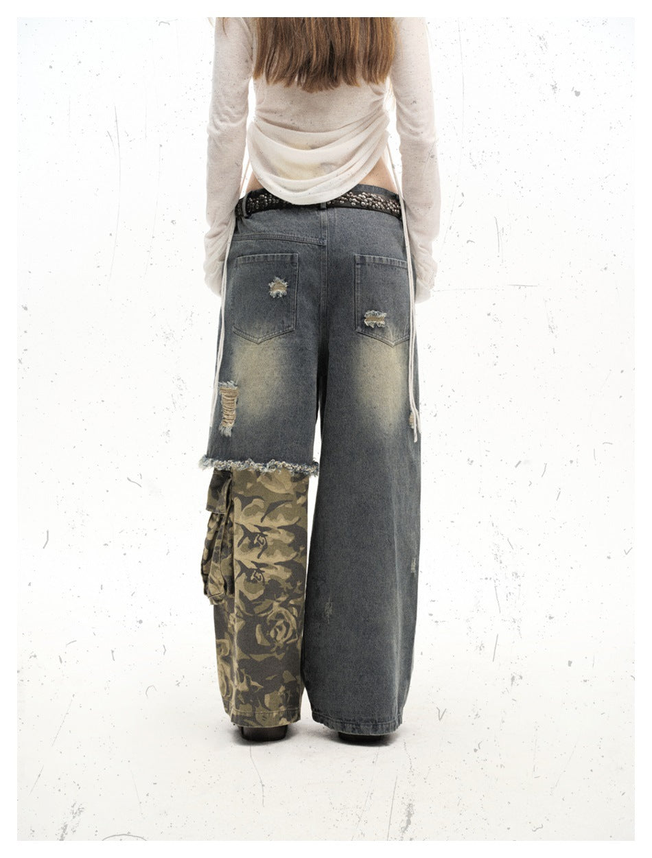 Back view of a model wearing oversized gray jeans with distressed pockets and one olive camouflage cargo leg.