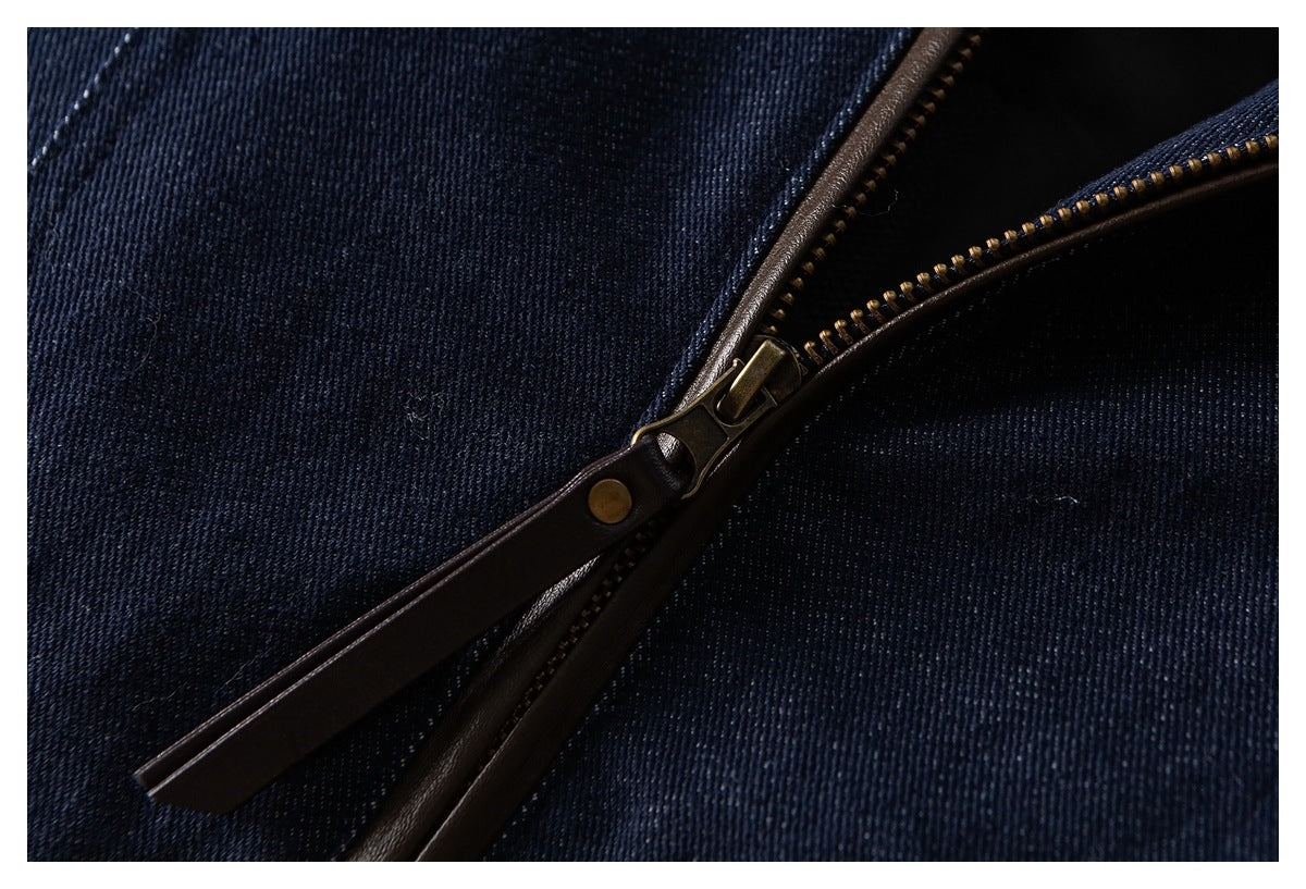 Close-up of a brass zipper with a dark brown pull on navy fabric.