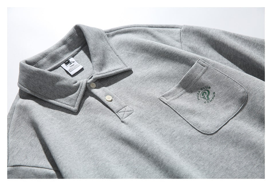 Angled close-up of the gray pullover's collar, two-button placket, and chest pocket with green embroidery.