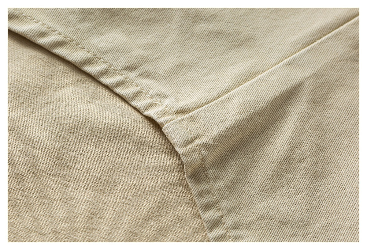 Close-up of beige twill jacket fabric and intersecting stitched seams.