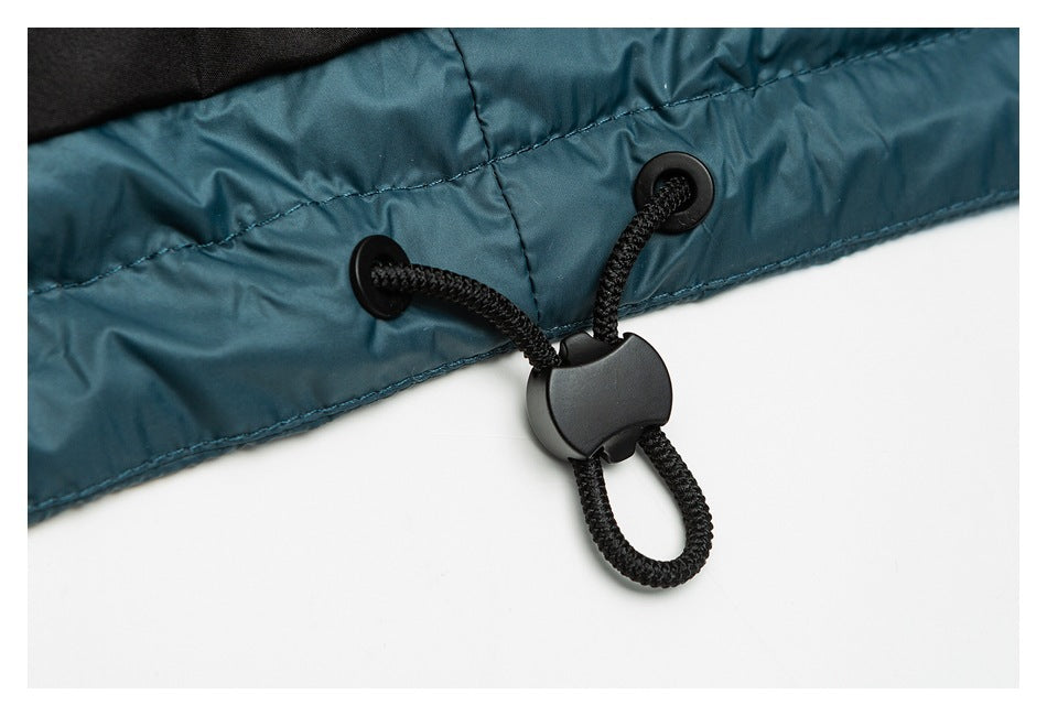 Close-up of a black cord-and-toggle adjuster attached to the teal hem of a padded garment.