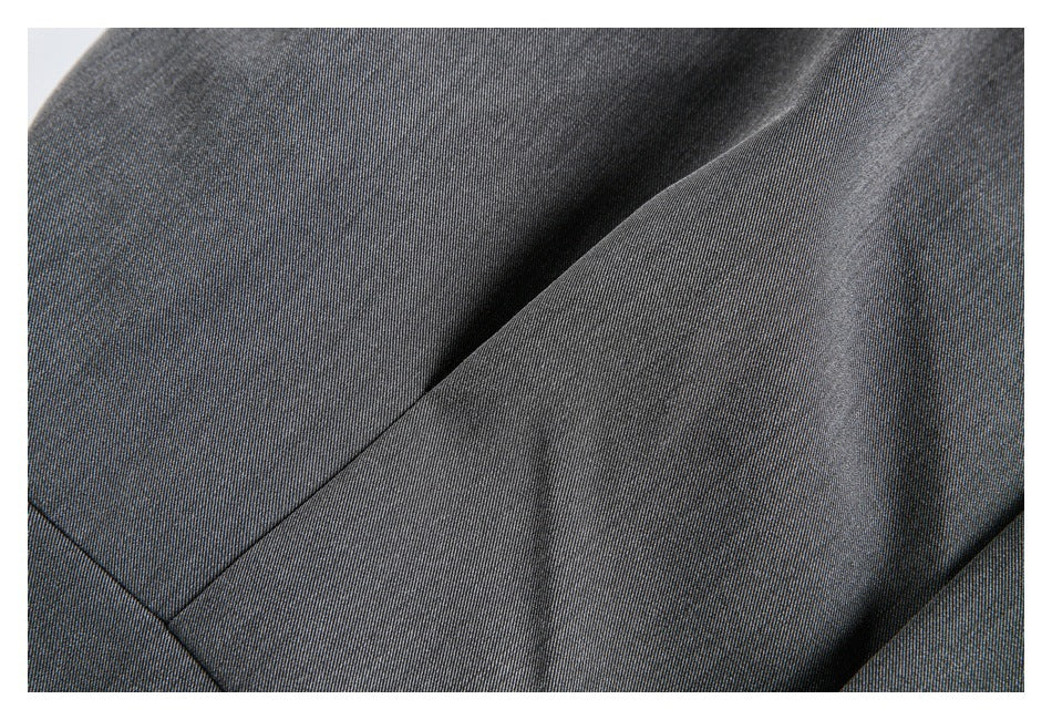 Close-up of dark charcoal fabric with a diagonal seam and overlapping folds.