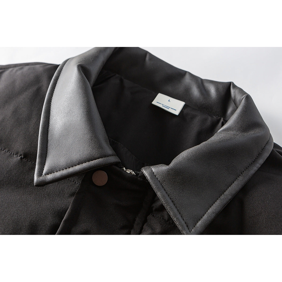 Close-up of a black jacket's wide collar, zipper and snap, with a small size label inside.