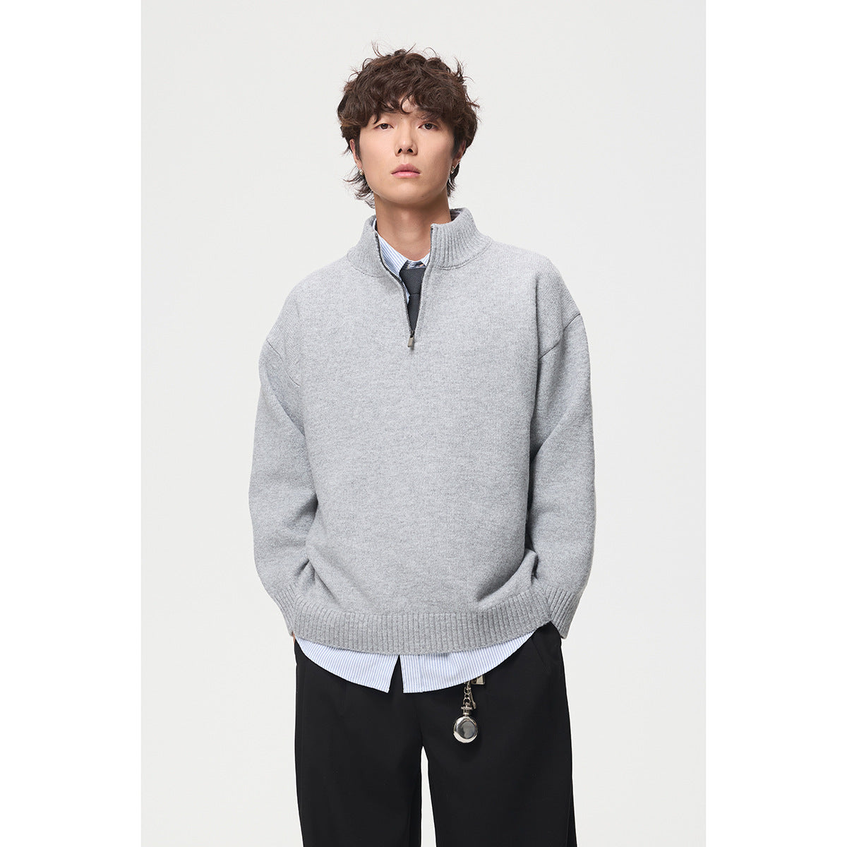 Model wearing a light gray quarter-zip sweater over a striped shirt and tie.