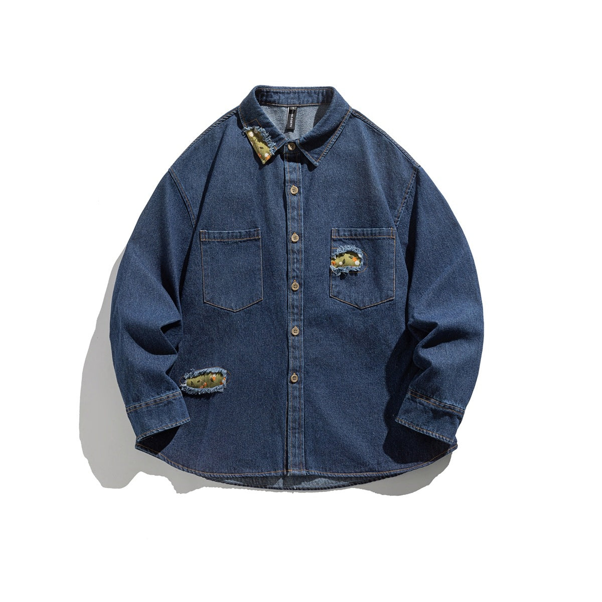 Washed blue denim shirt flat lay with button front, two chest pockets and frayed green floral patch cutouts