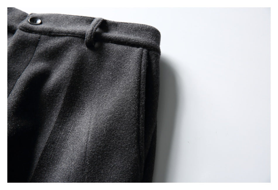 Close-up of charcoal gray trousers at the waistband, with a black button, belt loop, and side seam.