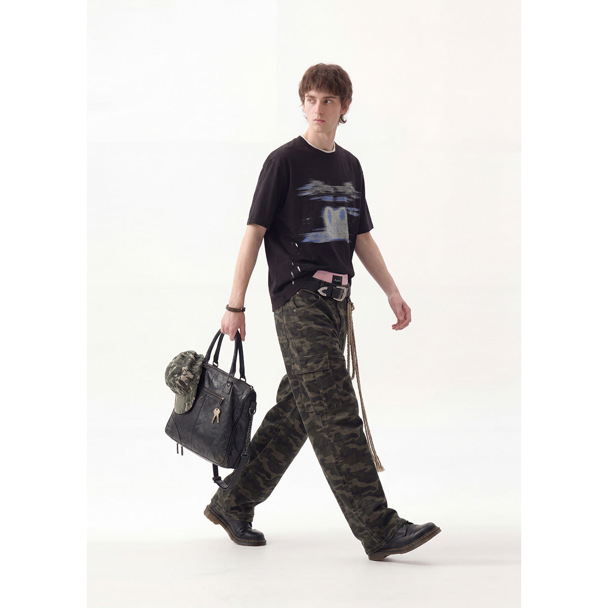 Full-length view of a model wearing a black graphic T-shirt and dark camouflage cargo pants.