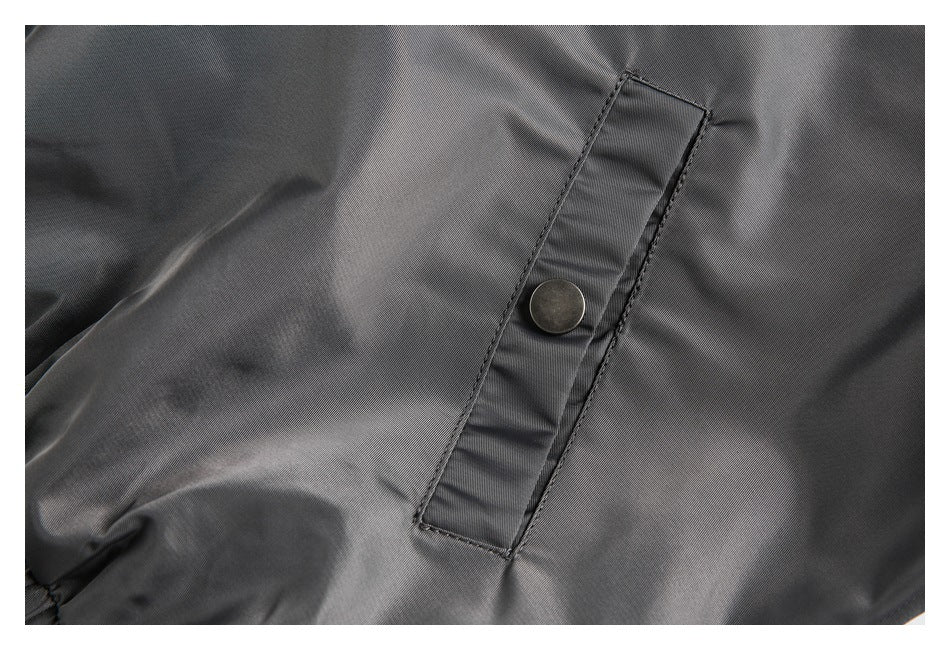 Close-up of a gray jacket with a narrow stitched tab and round metal snap.