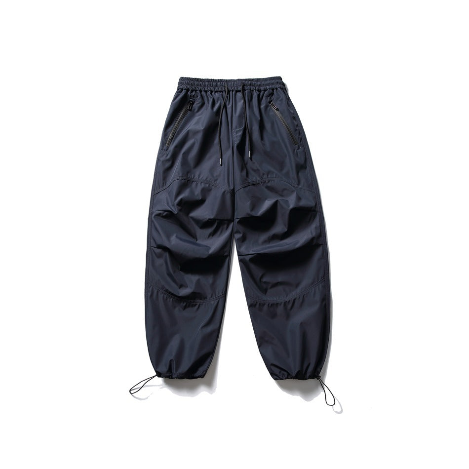 Navy drawstring pants flat lay with zippered pockets, curved knee seams and drawcord hems