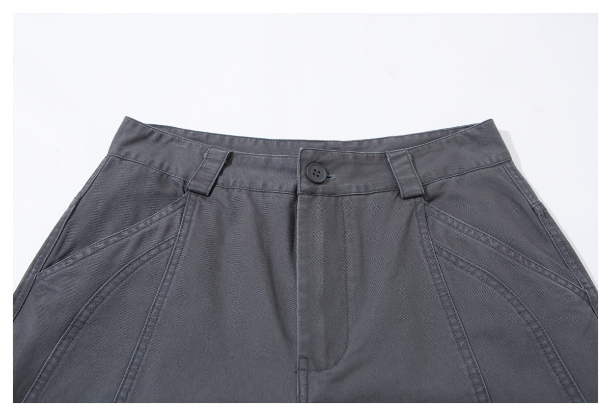 Close-up of slate-gray trousers showing the buttoned waistband, belt loops, fly, and curved front seams.