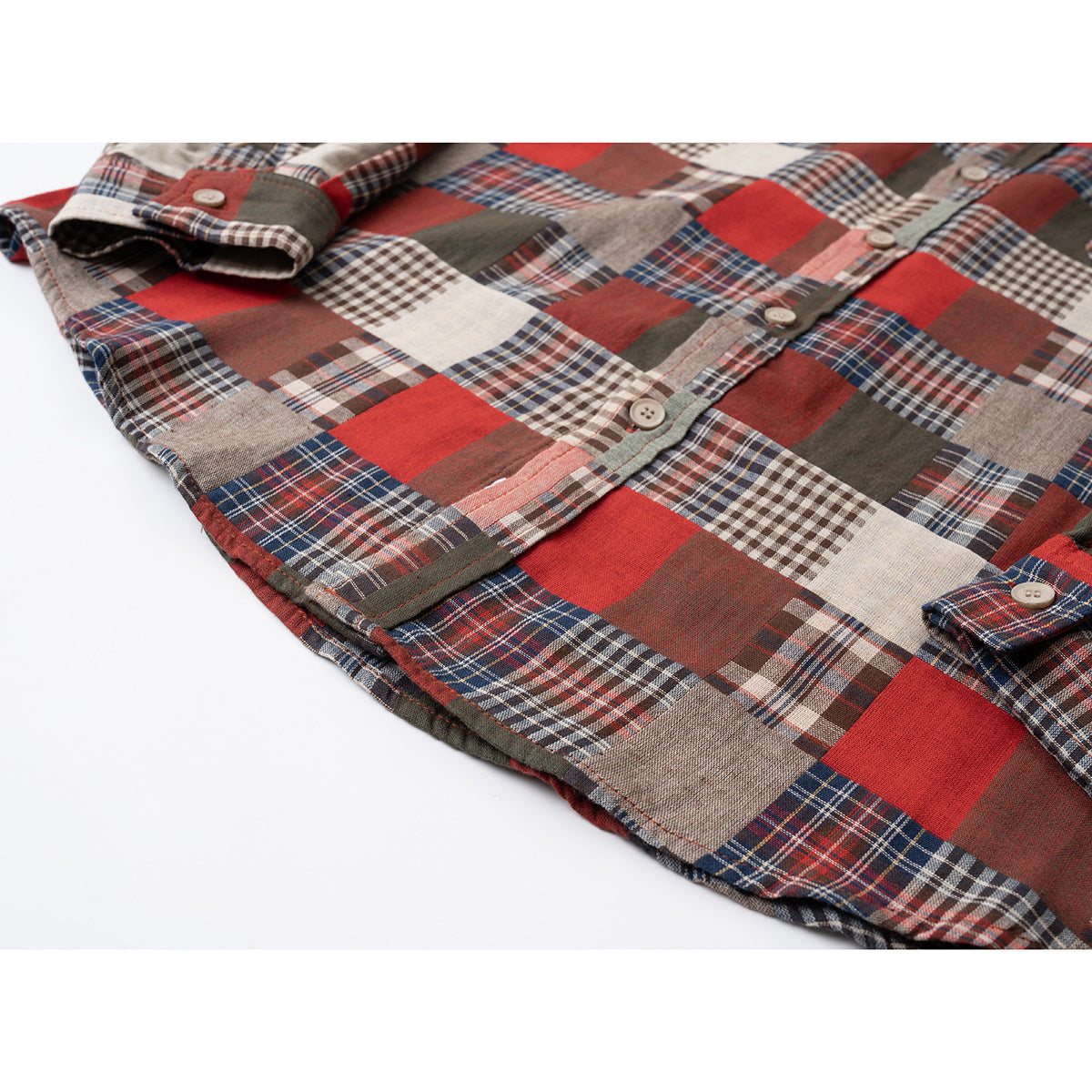 Angled flat lay of a red, cream, navy, and olive patchwork plaid button-up shirt.